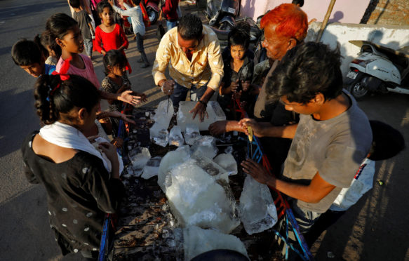 一个男人打破一块冰分发一个贫民窟的居民之一在炎热的天气在艾哈迈达巴德,印度,2022年4月28日