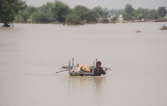 一个女人带着她的财产通过洪水拉,2022年8月,巴基斯坦