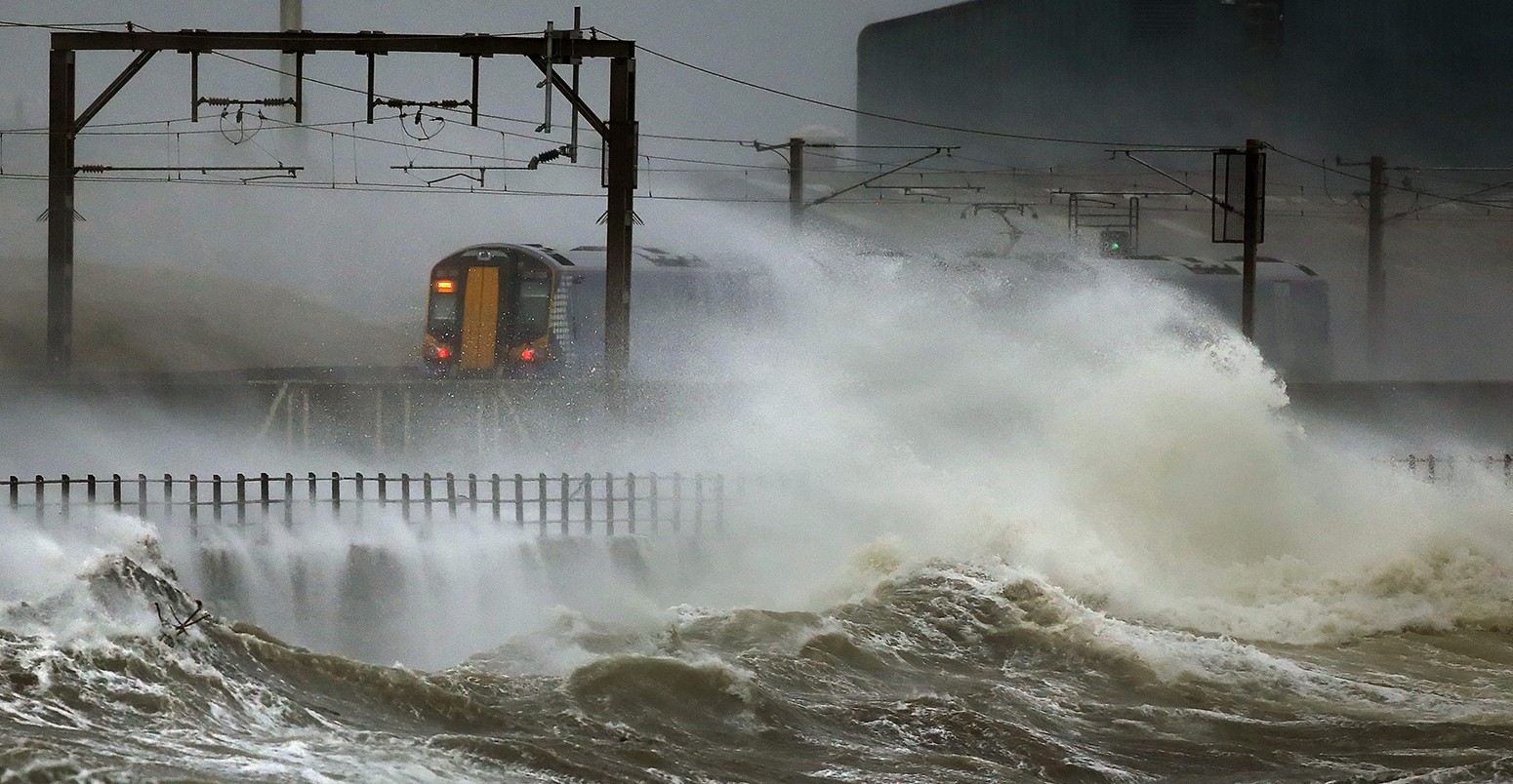 一列火车通过沿着海岸在苏格兰的Saltcoats饱受大海浪3 2014年1月