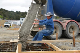 一名建筑工将水泥卡车上的湿混凝土导入一栋大楼的地基。