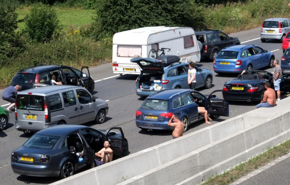 2016年7月30日，英国萨默塞特的一场热浪中，陷入交通堵塞的人们离开了他们的汽车。图片来源：蒂莫西·拉格/阿拉米股票照片。GFAT52