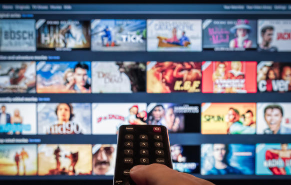 一个遥控器指出智能电视显示选择的流媒体视频点播服务