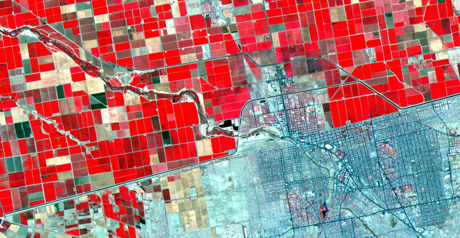 土地利用模式的卫星图像显示了戏剧性的差异在美国-墨西哥边境。郁郁葱葱的,定期网格农田美方与贫瘠的土地。