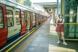 伦敦地铁乘客戴着面罩站在平台使用风扇来降温的炎热和潮湿的条件下在8月热浪。