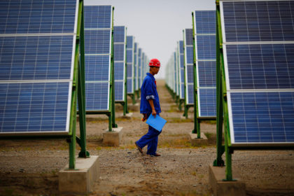 在敦煌的太阳能农场，一名工人正在检查太阳能电池板