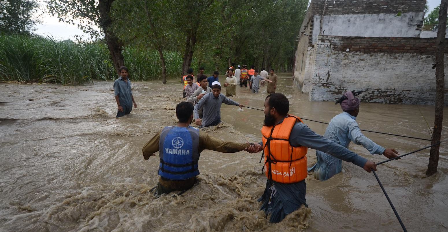 公民使他们与困难在被水淹没的街道上前行Dagai Mukaram汗地区,巴基斯坦。