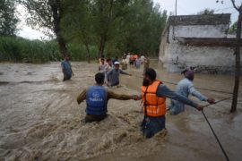 公民使他们与困难在被水淹没的街道上前行Dagai Mukaram汗地区,巴基斯坦。