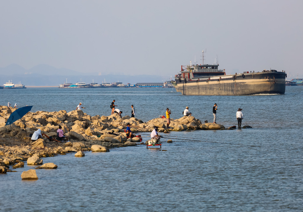 鱼人在炎热的天,一艘货船旅行在中国最大的淡水湖鄱阳湖,江西,2022年8月28日。