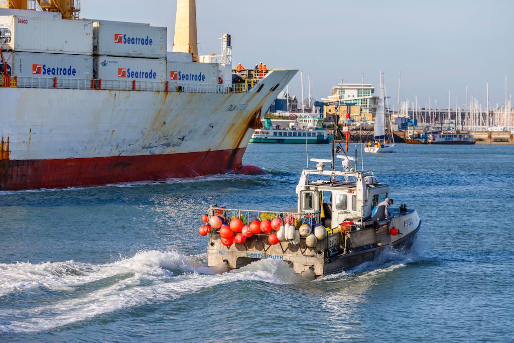 一个小传统的渔船是小巫见大巫了路过附近的一个大型集装箱船通话软管在朴茨茅斯港口,2020年1月18日。